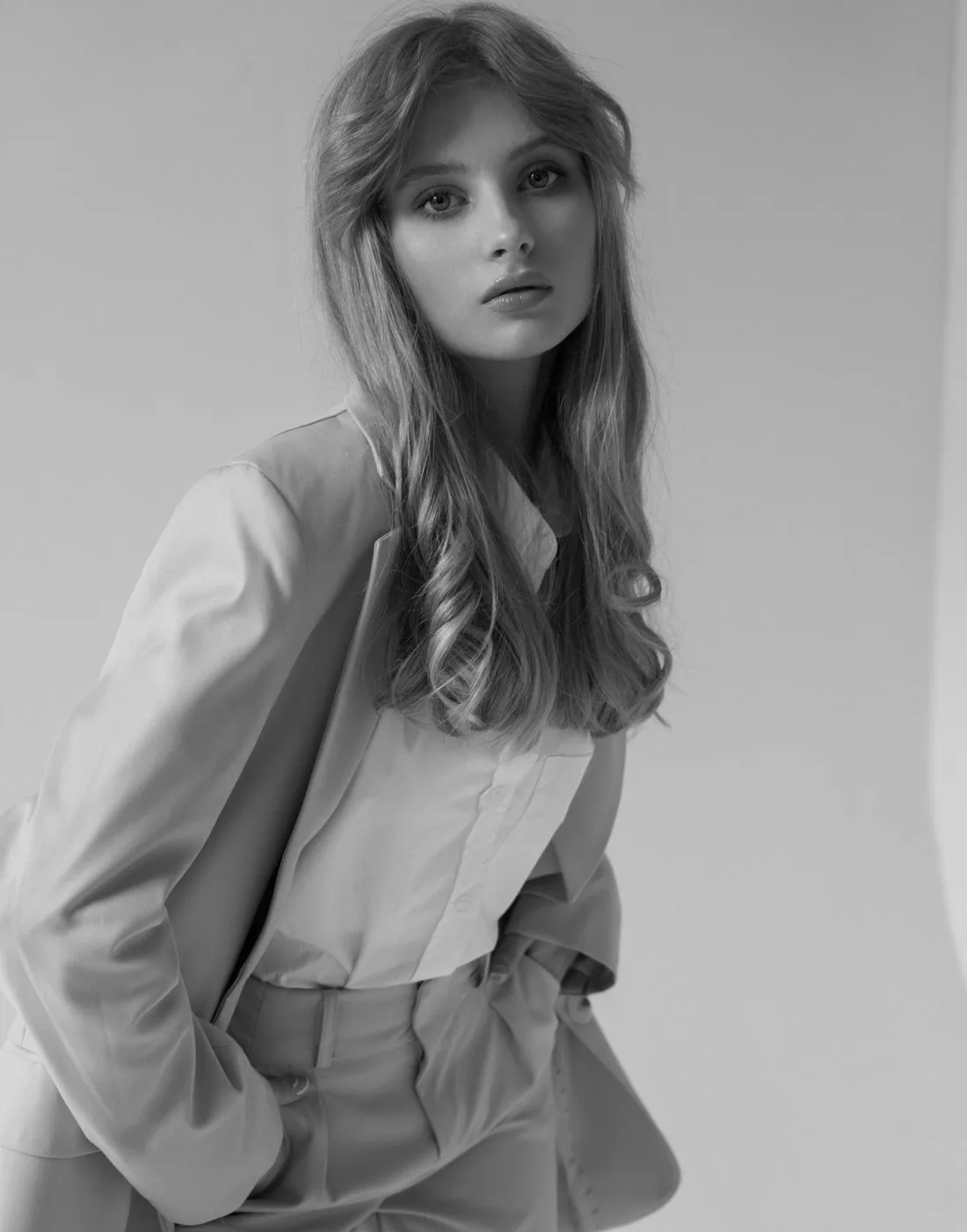 A quiet, considered tailored look: a woman in a soft suit with hands in pockets.